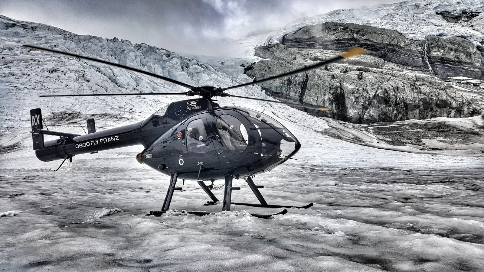 Dark grey helicopter on rocky snow in black and white high-contrast processing